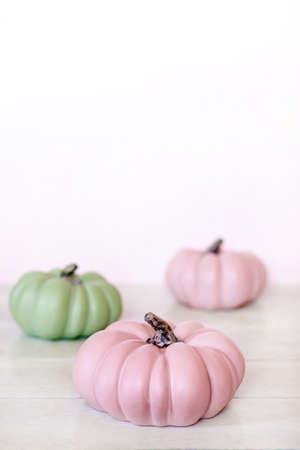 Autumn background with pink and green pumpkins and leaves in pastel shades on light background.の写真素材