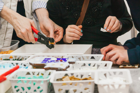 Master class on making mosaic panels for children. The hands of a master cutting off a piece of glass and children's hands close-upの写真素材