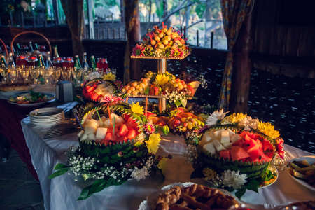 Fruit table with Canape appetizer: carved watermelons filled with pieces of melon and watermelon pulp, decorated with fresh flowers.の写真素材
