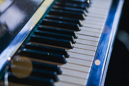 The keys of an old vintage piano in the background light with highlights. Close-up, selective focusの写真素材
