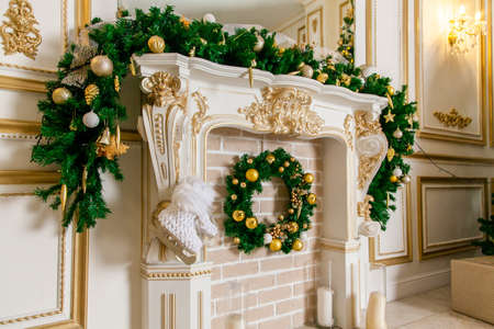 Fireplace with a fir wreath, decorative skates, fir tree garland with Christmas toys, balls on a spruce branch on Christmas tree.の写真素材