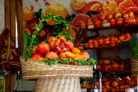 Basket basket decorated with fresh green leaves with juicy ripe pomegranate fruits and oranges prepared for squeezing juice in a street cafe.の写真素材