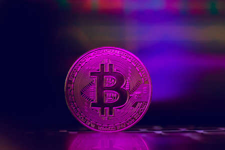 Bitcoin on the background of a graph on a laptop in neon light. Cryptocurrency.