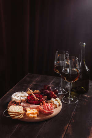 wine appetizer. Sausage and cheese cut with fruit, cookies and sauce with two glasses of white port and a bottle.の写真素材