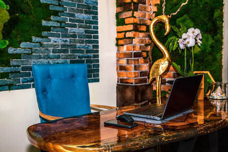 The workplace of an interior designer. Epoxy resin table, brick wall decorated with stabilized moss, laptop, smartphone.の写真素材