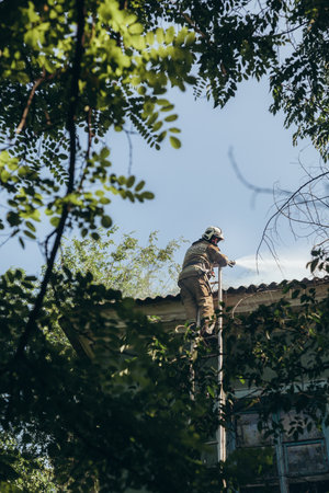 Russia, Rostov-on-Don - June 2, 2022: A firefighter stands on the stairs and extinguishes a fire on...