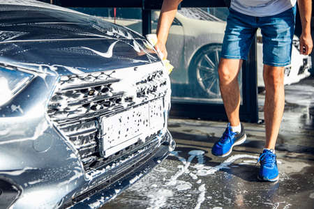 A man washes his car with foam at a self-service car wash.の写真素材