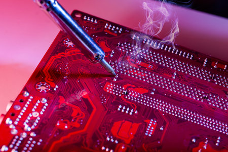 A man soldering a motherboard. Repair and maintenance of desktop personal computers and laptops.