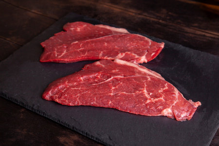 Raw minute steak of marbled beef on a stone slate board.の写真素材