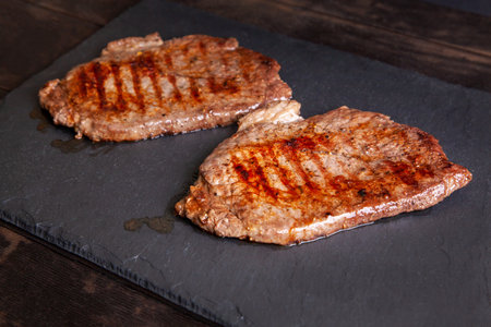 Grilled minute steak of marbled beef on a stone slate board, close up.の写真素材