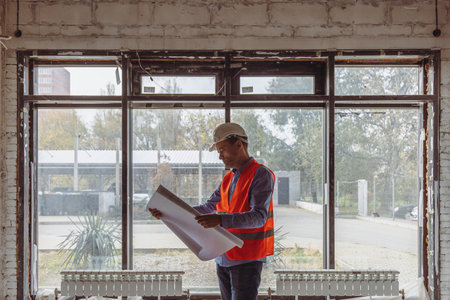 The foreman at the construction site is carefully studying the project, controlling the process of...