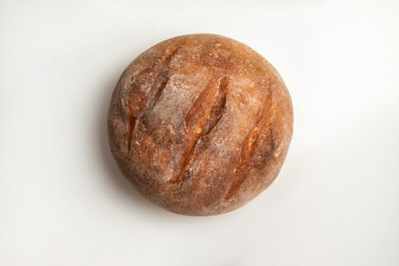 The round loaf of bread shows a golden brown crust and visible scoring on its surface. It sits on a...