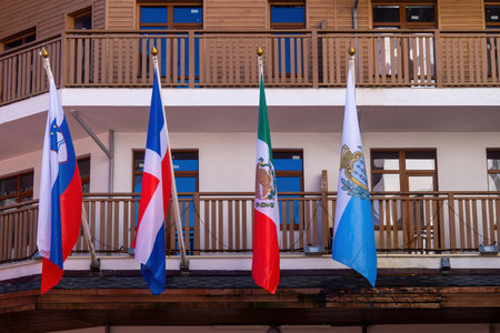Several national flags are hanging from a balcony of a modern building in a vibrant area. The flags represent diverse countries, showing a blend of cultures and nations.の写真素材