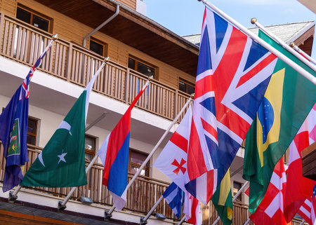A lively scene features flags from various countries hanging above a cozy walkway in a mountain resort.の写真素材