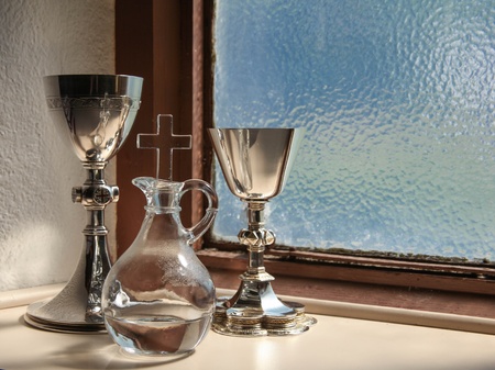 Holy communion items inside a church sacristy with a blue, lead glass window in the backgroundの写真素材