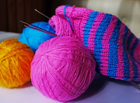 Pink, blue and yellow woollen balls, knitting-needles and half-knitted sockの写真素材