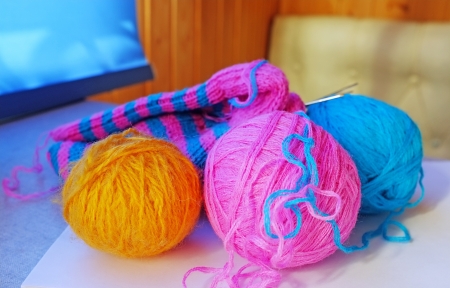 Pink, blue and yellow woollen balls, knitting-needles and half-knitted sockの写真素材