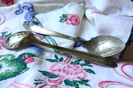 Table-cloth and table-napkins with embroidered parrot, flowers and decorative ornament with two spoons lying on itの写真素材