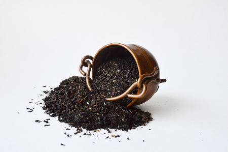 Overturned three-leg copper pot with half-spilled black teaの写真素材