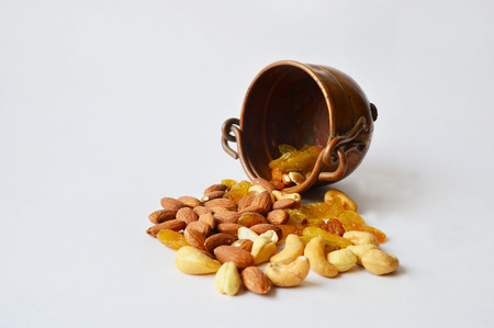 Overturned three-leg copper pot with nuts and raisinsの写真素材