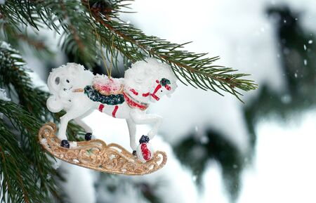 Christmas antique retro white horse toy on the snow branch of a green tree. Snow lies on the branches of fir tree. Christmas decor. Christmas winter concept. Copy space for text font words. Top view の写真素材