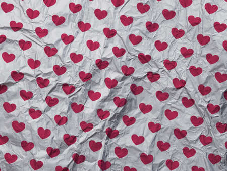 Crumpled gray paper texture with red hearts pattern. Grunge background best for Valentines Day.