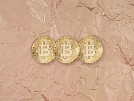 Cryptocurrency Bitcoin on crumpled gold paper background.