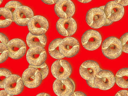 Fresh homemade bagels with poppy seeds on red background. Wheat and rye rolls in the shape of a ring, with sprinkles of poppy seeds.の写真素材