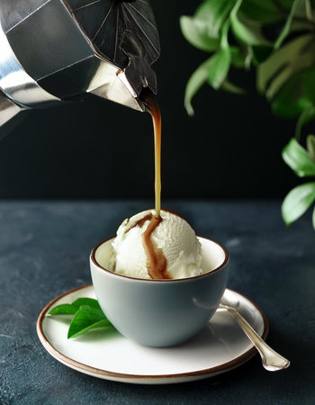 Espresso pouring over vanilla ice cream creating a delicious affogato dessert in a white cup.の写真素材