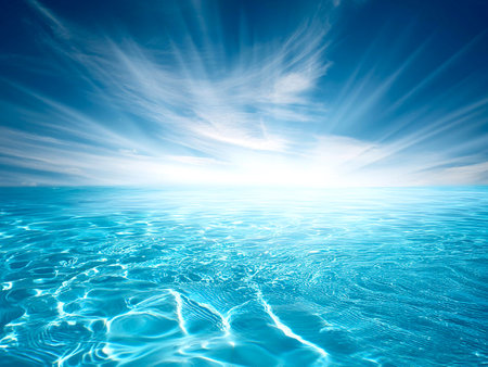 Sun rays illuminate a vast blue ocean, casting shimmering reflections on the water's surface in a peaceful scene.の写真素材