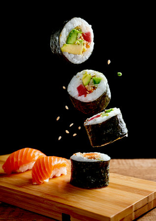 A beautifully arranged platter of sushi displayed on a rustic wooden cutting board, showing vibrant colors and textures.の写真素材