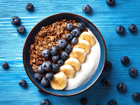 Simple rustic breakfast - yogurt granola bowl with blueberries, banana and chocolate. Top view.の写真素材