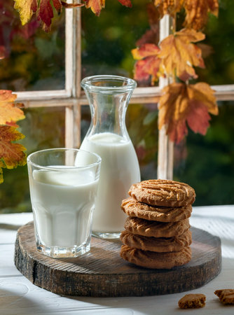 Fresh milk and shortbread cookies stacked close together, showing their rich brown color and texture. A rustic autumnal arrangement.の写真素材