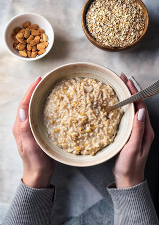 Oatmeal porridge bowl in female hands. Clean eating, dieting, vegetarian breakfast food for weight loss concept.の写真素材