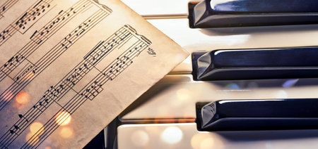 Close-up of piano keys with a sheet of music in the foreground, capturing the essence of classical music and composition. Ideal for topics related to piano lessons, music theoryの写真素材