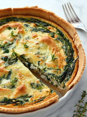 Spinach, shallot, and goat cheese crustless quiche with thyme on white marble table. A fresh and flavorful homemade dish for spring brunch.の写真素材