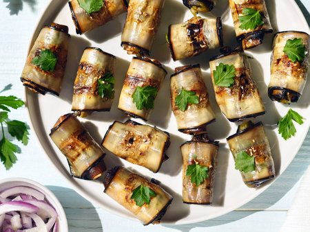 Georgian eggplant rolls (nigvziani badrijani) filled with walnuts, garlic and spices, garnished with fresh cilantro and pickled red onions on a white plate. Tasty and unusual dishの写真素材