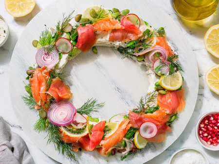 Festive appetizer wreath with smoked salmon, cream cheese, lemon slices, dill, capers, and red onion on marble platter. Perfect for holiday gatherings and seafood lovers.の写真素材