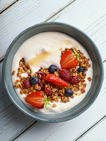 Title A breakfast yoghurt bowl with nectar roasted strawberries, crunchy chocolate granola nuggets, a handful of fresh berries and a splash of maple syrup.の写真素材
