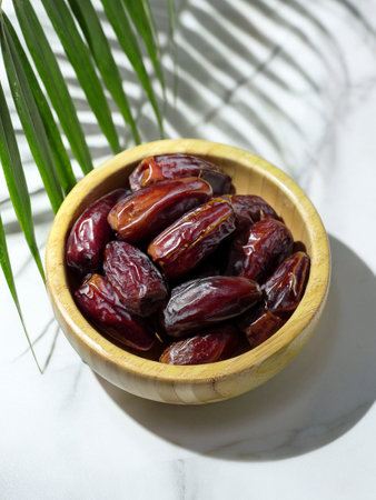 Bowl containing dates placed on a sleek marble table, highlighting the natural colors of the dates...