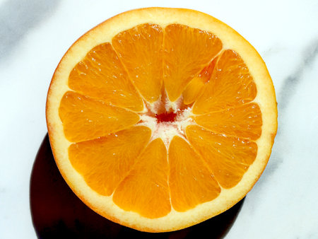 Sliced orange on marble surface, showing juicy segments and vibrant color, perfect for healthy eating and vitamin C boost.の写真素材