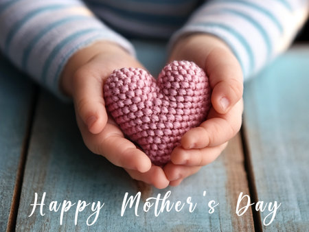 Child holding a pink knitted heart, with Happy Mother's Day text overlay, symbolizing love and appreciation for mothers on Mother's Day.の写真素材