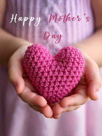 Child holding a pink knitted heart, with Happy Mother's Day text overlay, symbolizing love and appreciation for mothers on Mother's Day.の写真素材