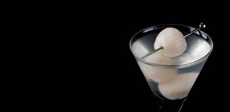 Sake and lychee martini with fresh lychee fruit, elegantly displayed on a black background. Space for text.の写真素材