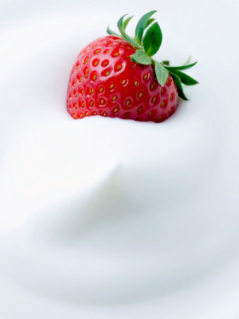 A single strawberry is placed in a bowl of plain yogurt. Close-up detail highlights the wonderful textures of the healthy snack. Space for text.の写真素材