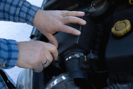 Mans Hands Using Tools to Repair a Car Engine Beneath the Open Hood, Mechanical Expertise in Automotive Maintenanceの写真素材