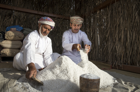 Muscat, Oman, February 4th, 2017: men in traditional clothing with a pile of saltのeditorial素材