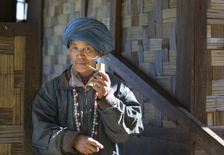 Chin region, Myanmar, November 11, 2014: chin woman smoking a pipe outside her house