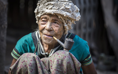 Chin region, Myanmar, November 11, 2014: muun tribe chin lady smoking a pipe