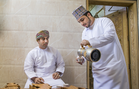 Nizwa, Oman, 26th May, 2016: omani man serving traditional coffee called qahwa to another omani manのeditorial素材